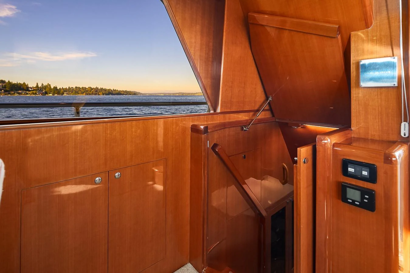 A polished wooden staircase leads to the lower deck, with a view of the serene waters outside. aboard LA BELLA VITA II Yacht for Sale