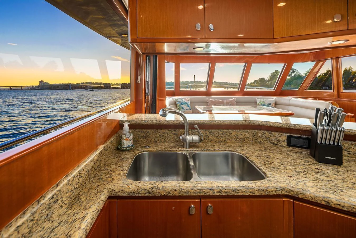 The galley features a sleek granite countertop with a double sink and a set of knives, offering a stunning view of the water through large windows. aboard LA BELLA VITA II Yacht for Sale