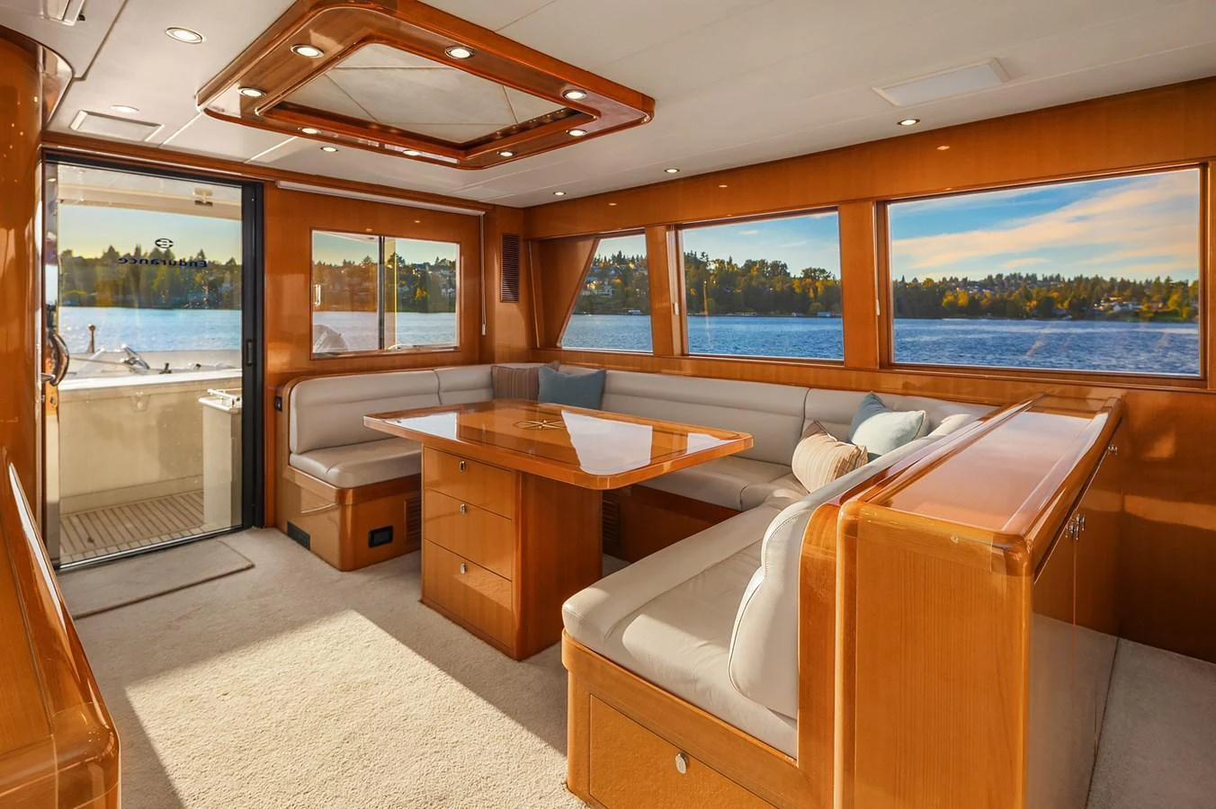 The salon features elegant wood finishes, large windows, and comfortable seating with a view of the water. aboard LA BELLA VITA II Yacht for Sale