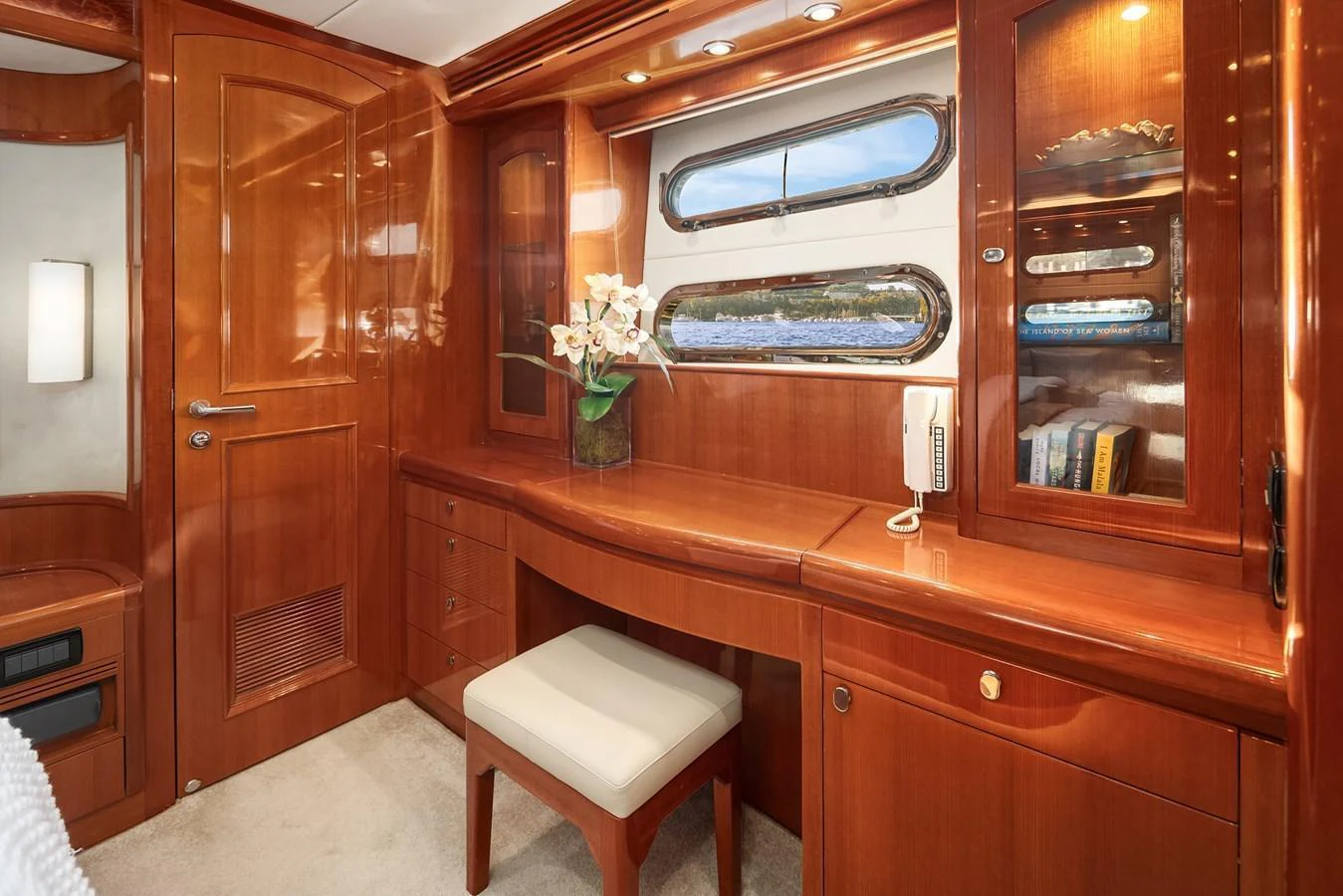 The stateroom features elegant wood cabinetry, a comfortable seating area, and a window with a scenic view. aboard LA BELLA VITA II Yacht for Sale