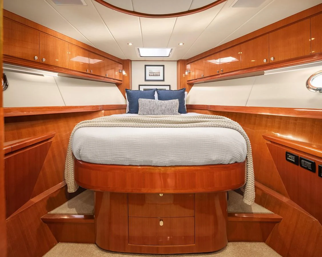 The stateroom features a luxurious bed with elegant wood paneling and ample storage. aboard LA BELLA VITA II Yacht for Sale