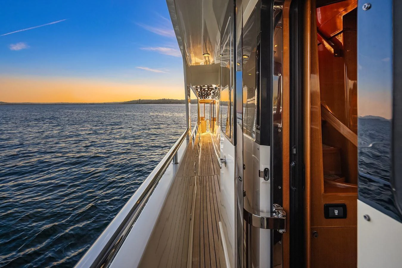 The side deck of the yacht offers a serene view of the water at sunset. aboard LA BELLA VITA II Yacht for Sale