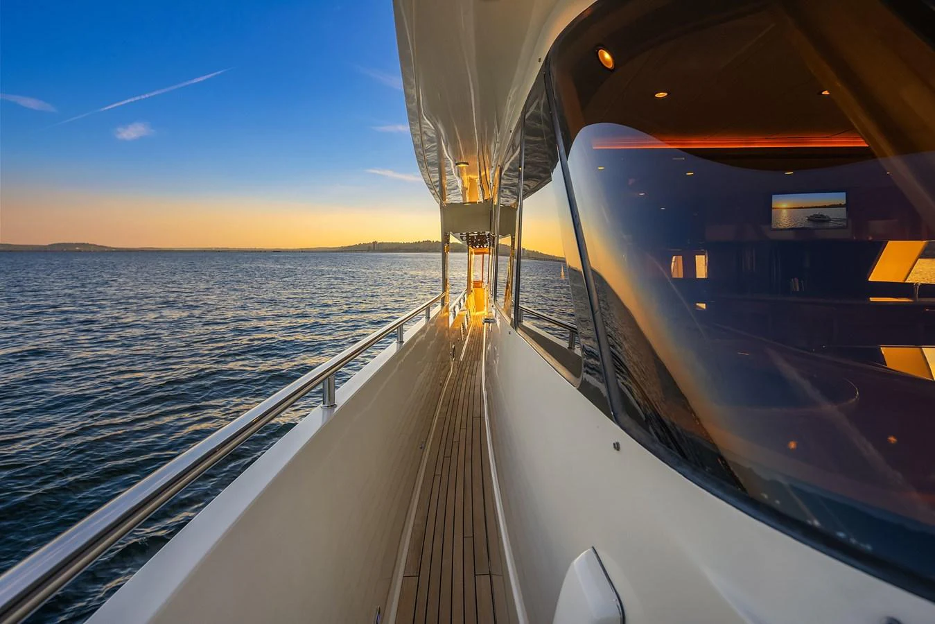 The yacht's sleek side deck offers a stunning view of the open water at sunset. aboard LA BELLA VITA II Yacht for Sale