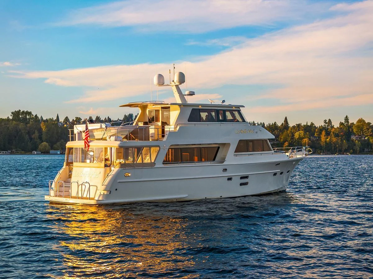 A luxurious yacht cruises on calm waters under a beautiful sunset sky. aboard LA BELLA VITA II Yacht for Sale