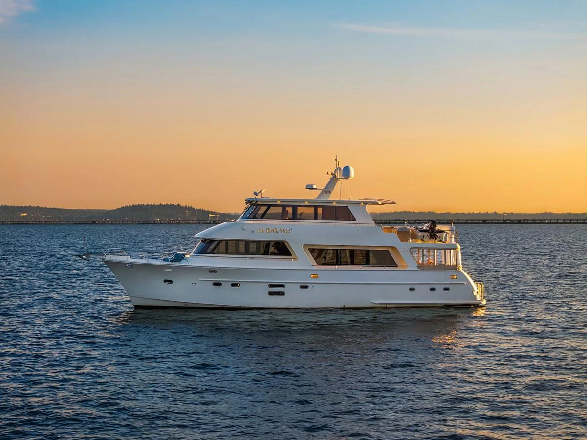 A luxurious yacht cruises on calm waters during a beautiful sunset. aboard LA BELLA VITA II Yacht for Sale