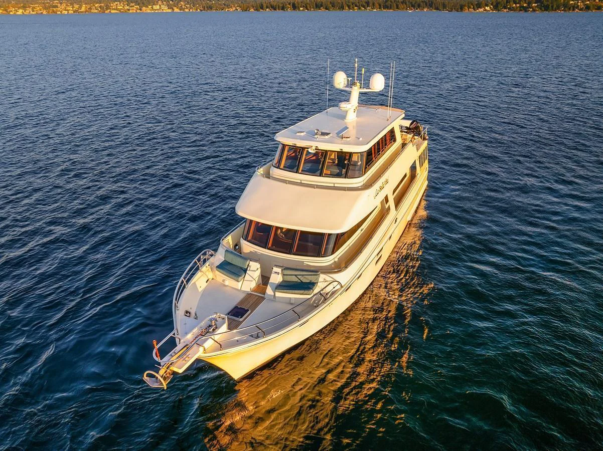 A luxurious yacht cruises gracefully on calm waters under a golden sunset. aboard LA BELLA VITA II Yacht for Sale