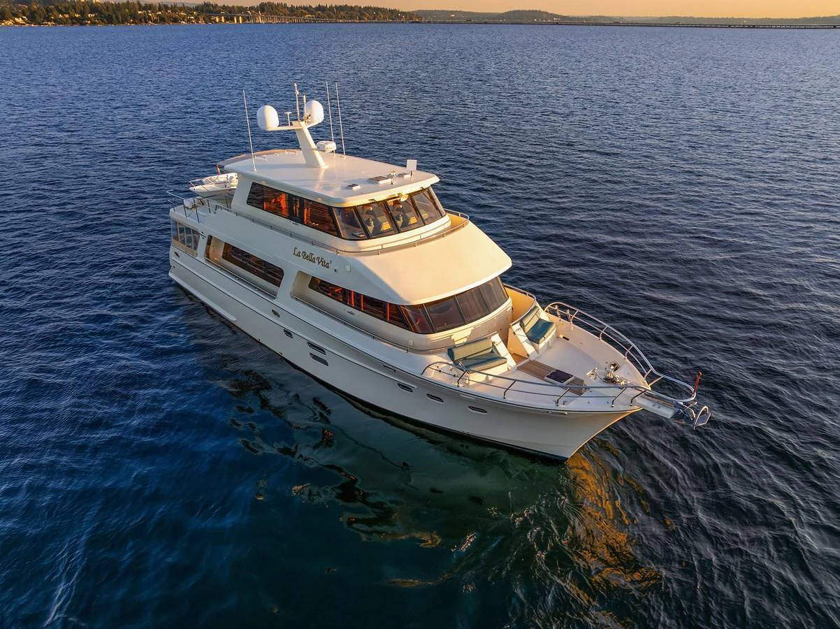 A luxurious yacht glides gracefully on calm waters under a golden sunset. aboard LA BELLA VITA II Yacht for Sale