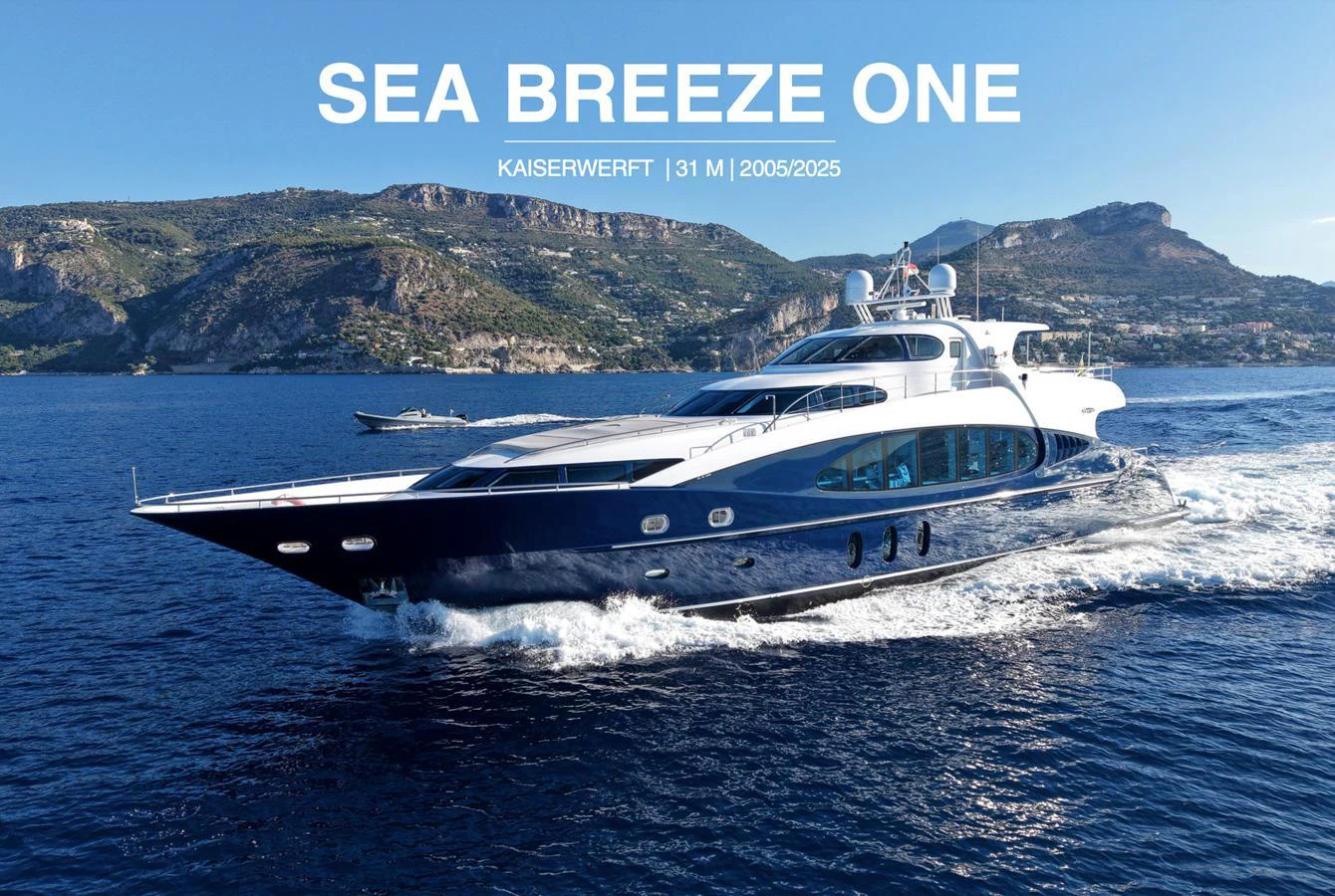 A sleek and elegant yacht cruises through clear blue waters with scenic mountains in the background. aboard SEA BREEZE ONE Yacht for Sale