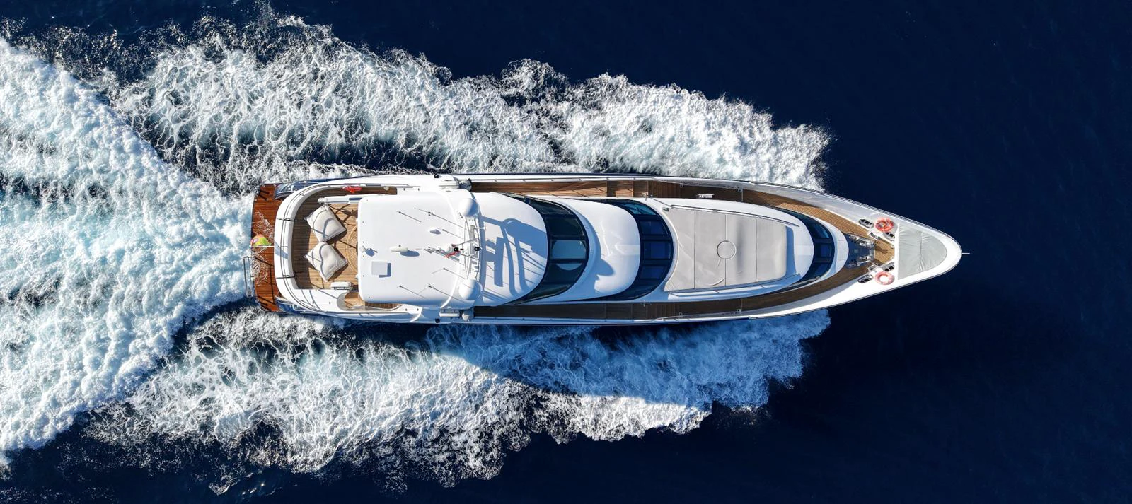 An aerial view of a luxurious yacht cruising through the deep blue sea, leaving a trail of white foam behind. aboard SEA BREEZE ONE Yacht for Sale