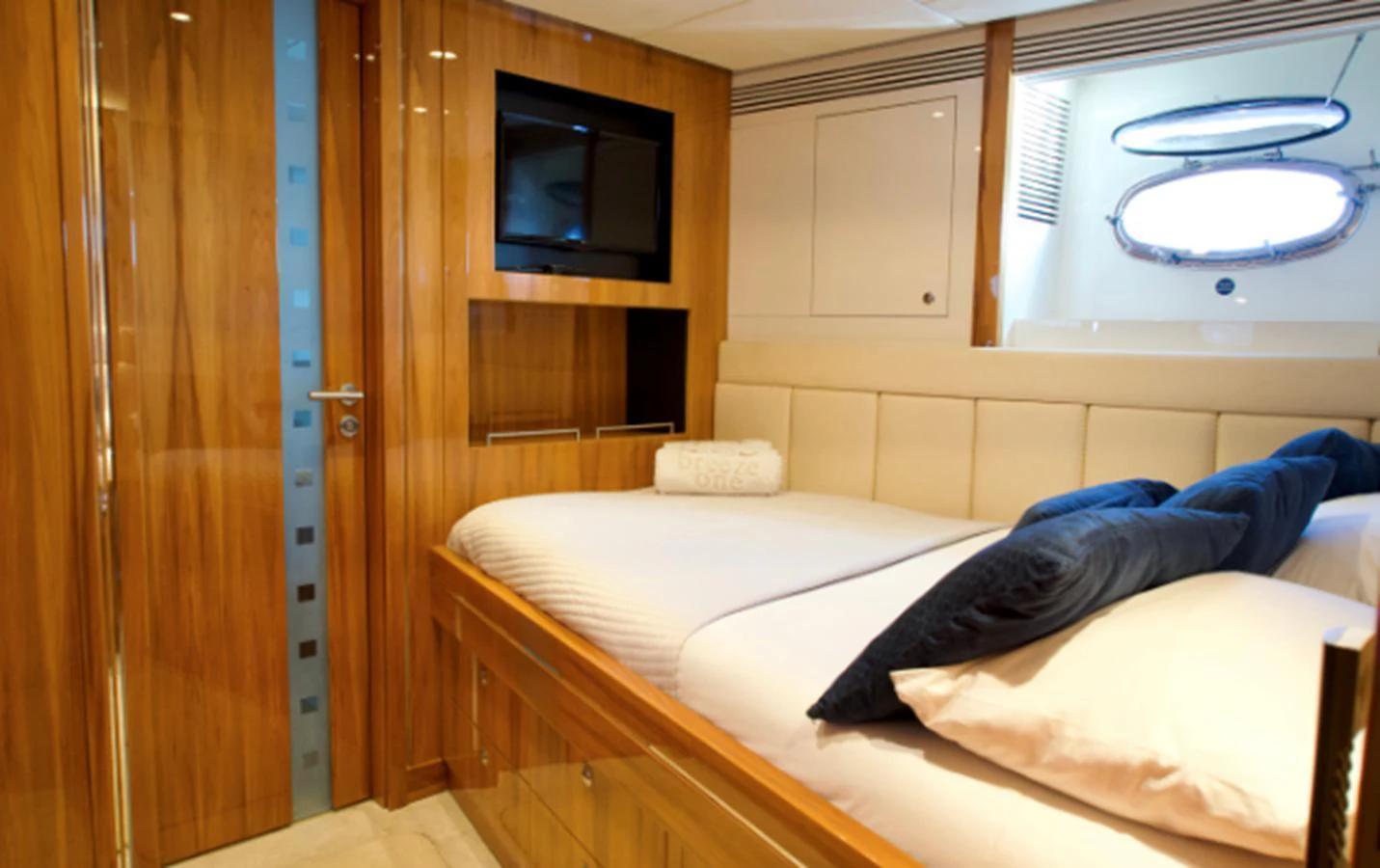 The stateroom features a cozy bed with plush pillows and elegant wooden finishes. aboard SEA BREEZE ONE Yacht for Sale