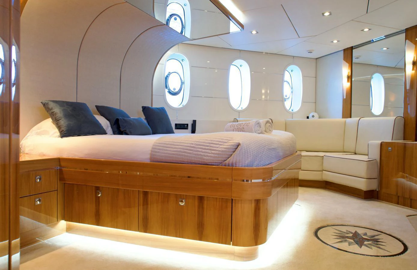 The master stateroom features a luxurious bed with elegant wood finishes and ample natural light from the portholes. aboard SEA BREEZE ONE Yacht for Sale