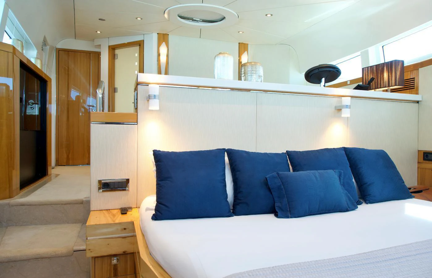 The stateroom features a plush bed with blue accent pillows and modern lighting. aboard SEA BREEZE ONE Yacht for Sale