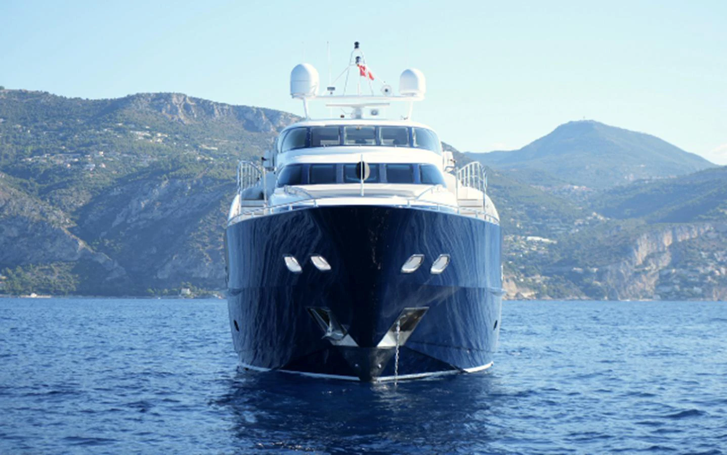 A sleek yacht is anchored on calm waters with a mountainous backdrop. aboard SEA BREEZE ONE Yacht for Sale