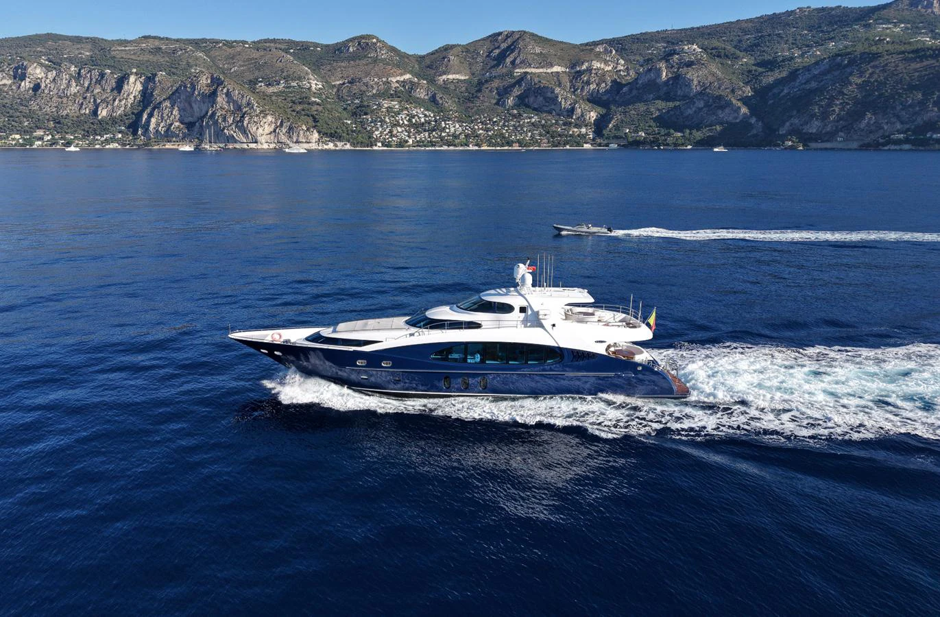 A sleek yacht cruises through calm blue waters with a scenic mountainous backdrop. aboard SEA BREEZE ONE Yacht for Sale