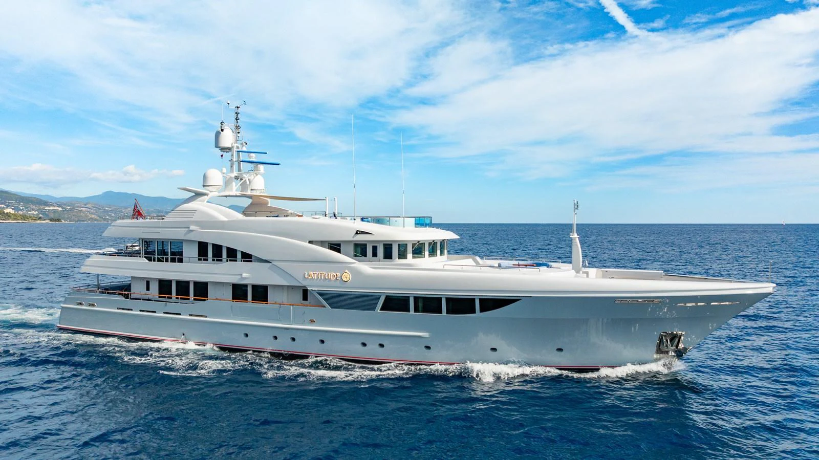 A sleek and elegant yacht cruises through the open water under a clear blue sky. aboard LATITUDE Yacht for Sale
