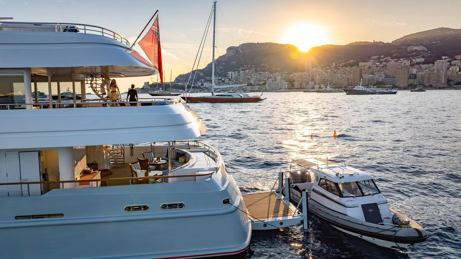 The yacht is docked at sunset with a tender alongside, showcasing a serene and luxurious setting. aboard LATITUDE Yacht for Sale