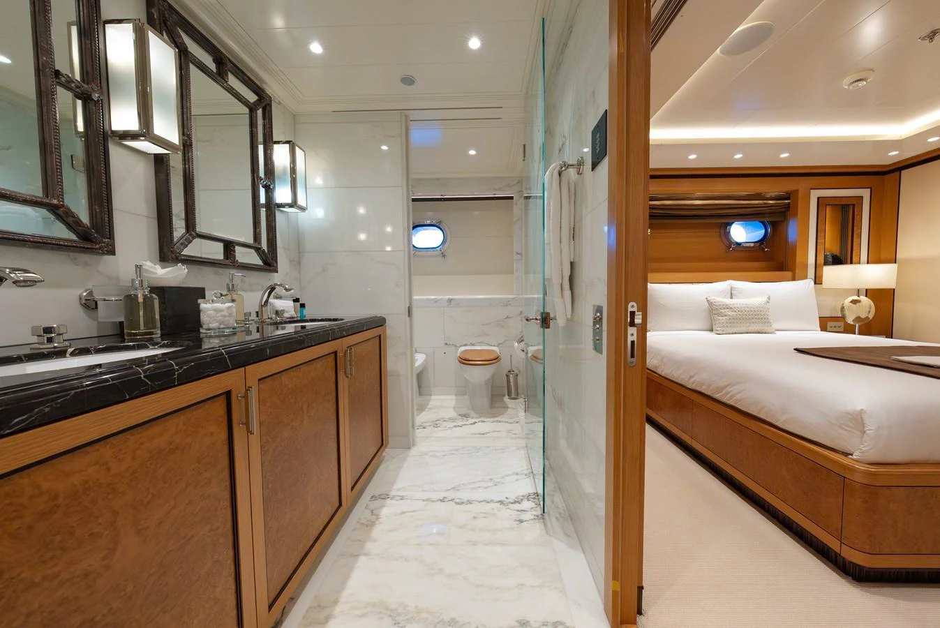 The image showcases a luxurious stateroom with an en-suite bathroom, featuring elegant wood finishes and modern amenities. aboard LATITUDE Yacht for Sale