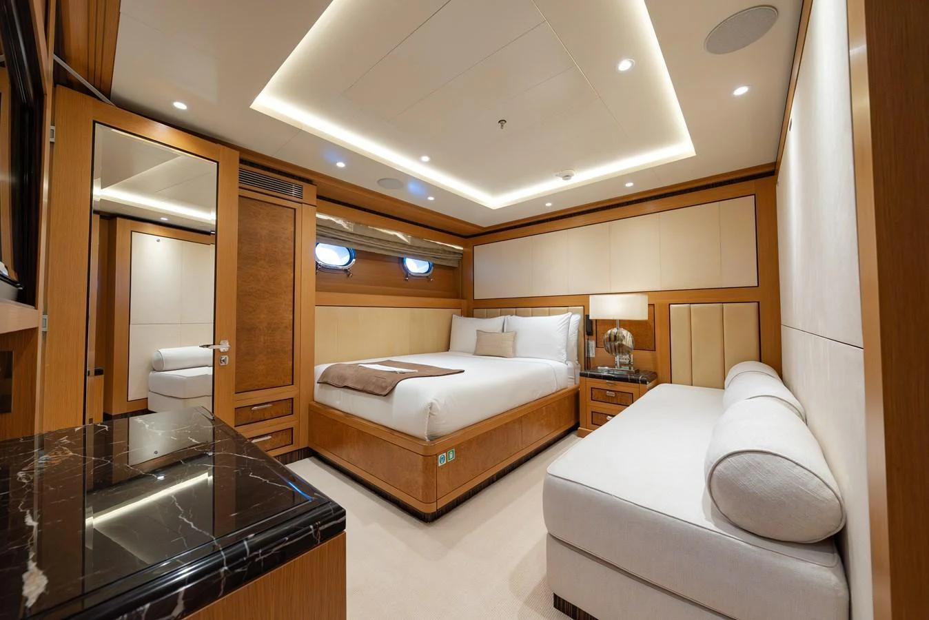 A luxurious stateroom featuring a large bed, elegant wood paneling, and ambient lighting. aboard LATITUDE Yacht for Sale
