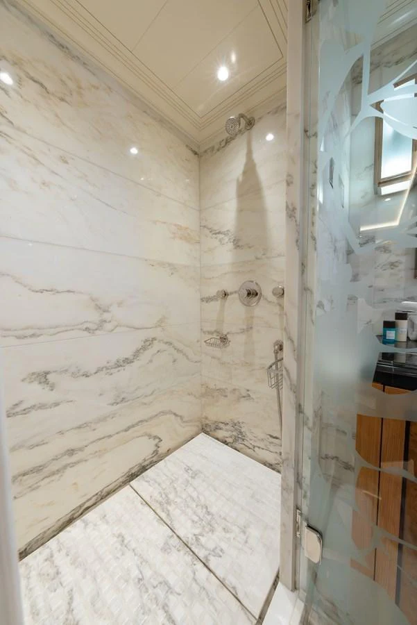 The yacht's bathroom features luxurious marble walls and a spacious shower area. aboard LATITUDE Yacht for Sale