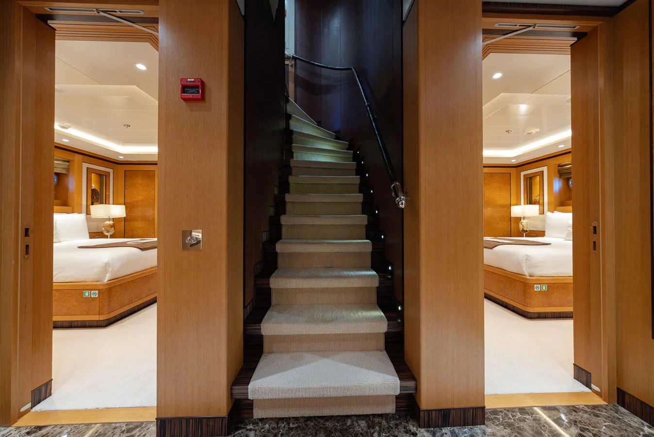 A luxurious interior staircase leads to the upper deck, flanked by two elegant staterooms. aboard LATITUDE Yacht for Sale