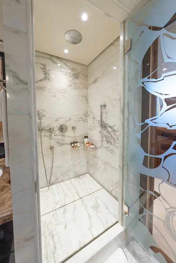 The yacht's bathroom features a luxurious marble shower with modern fixtures. aboard LATITUDE Yacht for Sale
