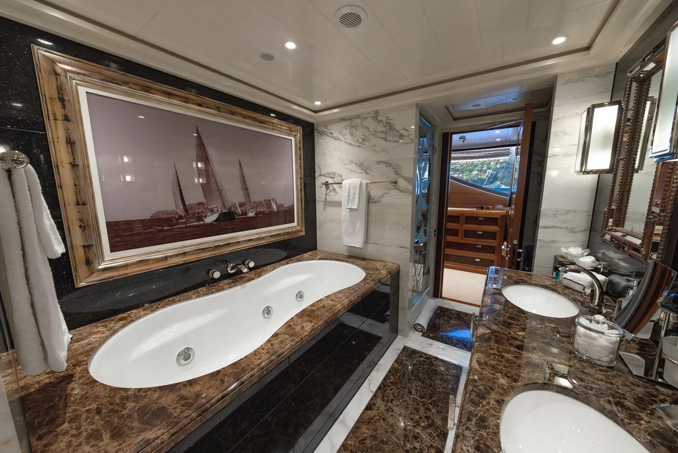 The yacht's bathroom features a luxurious marble countertop and a spacious bathtub, complemented by elegant fixtures and a large framed artwork. aboard LATITUDE Yacht for Sale