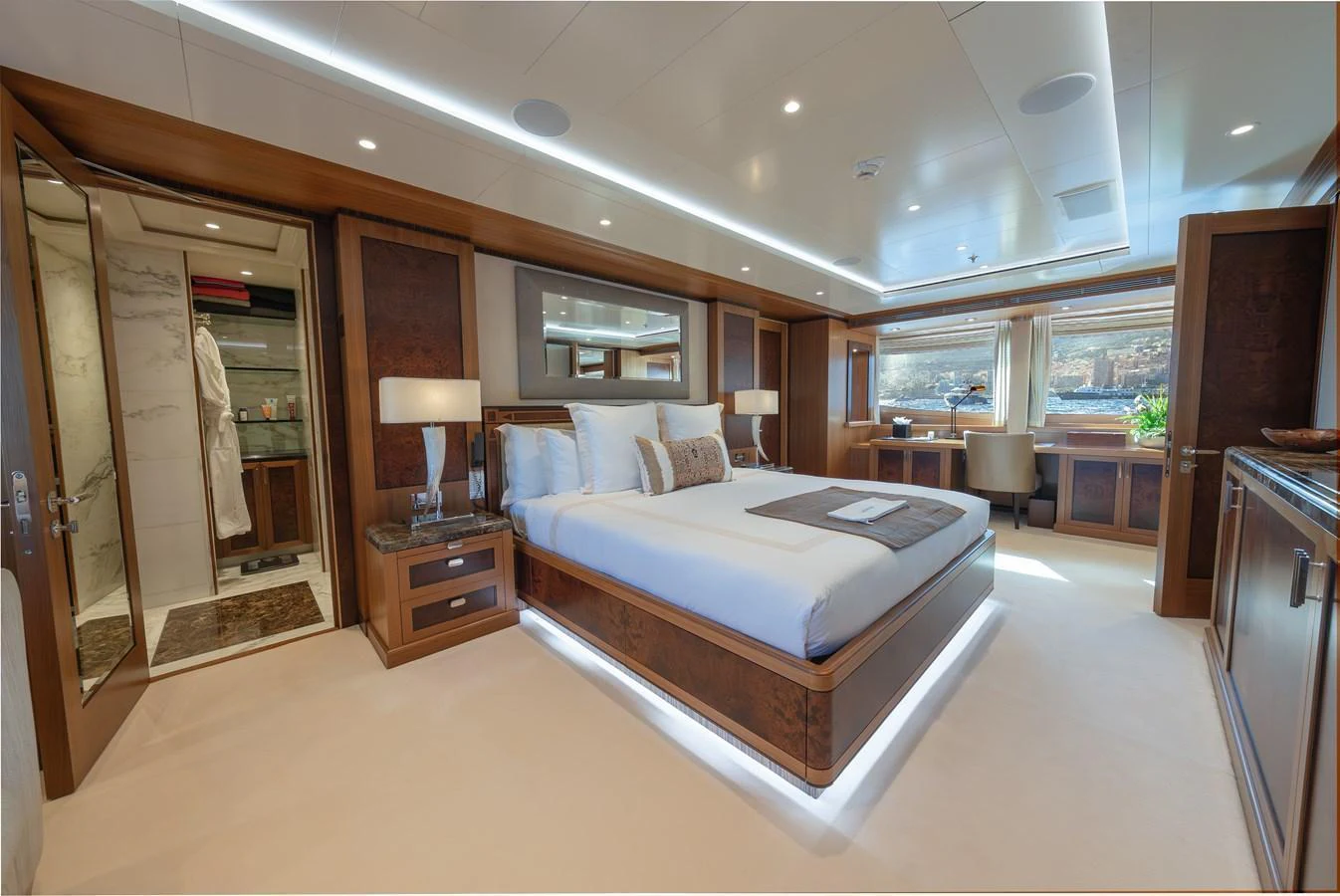 The master stateroom features a luxurious bed, elegant wood finishes, and ample natural light. aboard LATITUDE Yacht for Sale