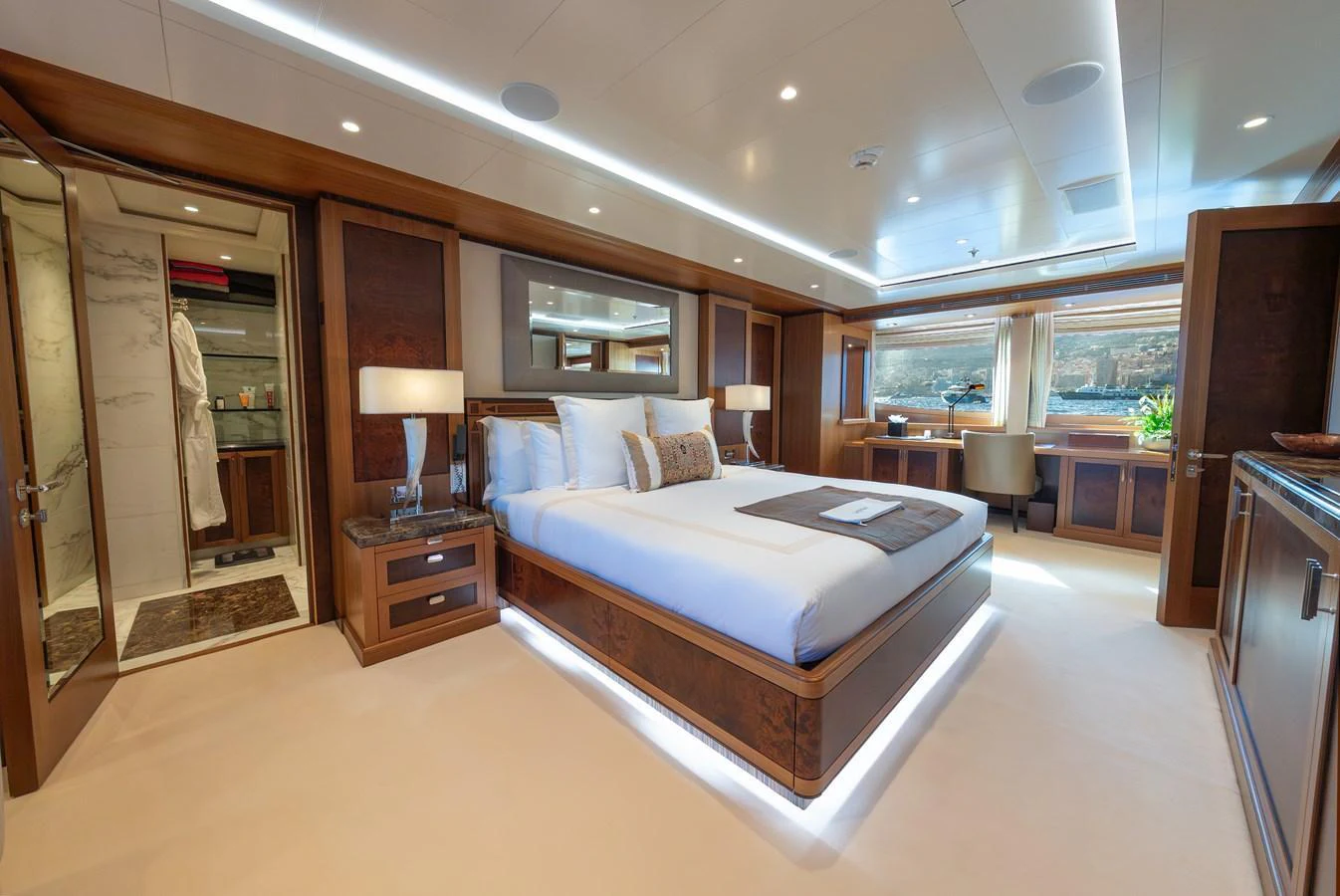 The master stateroom features a luxurious bed, elegant wood finishes, and ample natural light. aboard LATITUDE Yacht for Sale