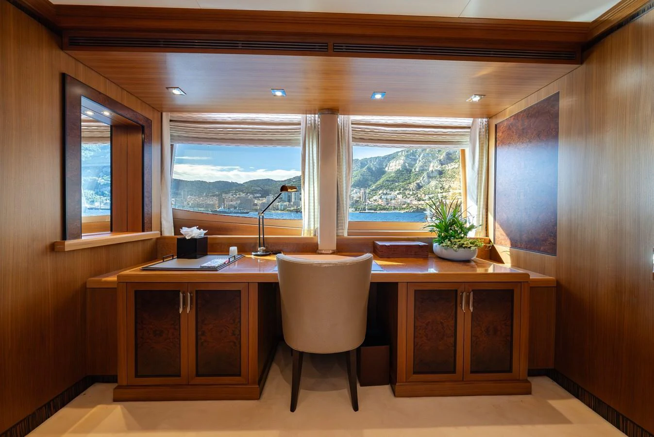This elegant yacht office features a large desk with a comfortable chair and a scenic view through the windows. aboard LATITUDE Yacht for Sale