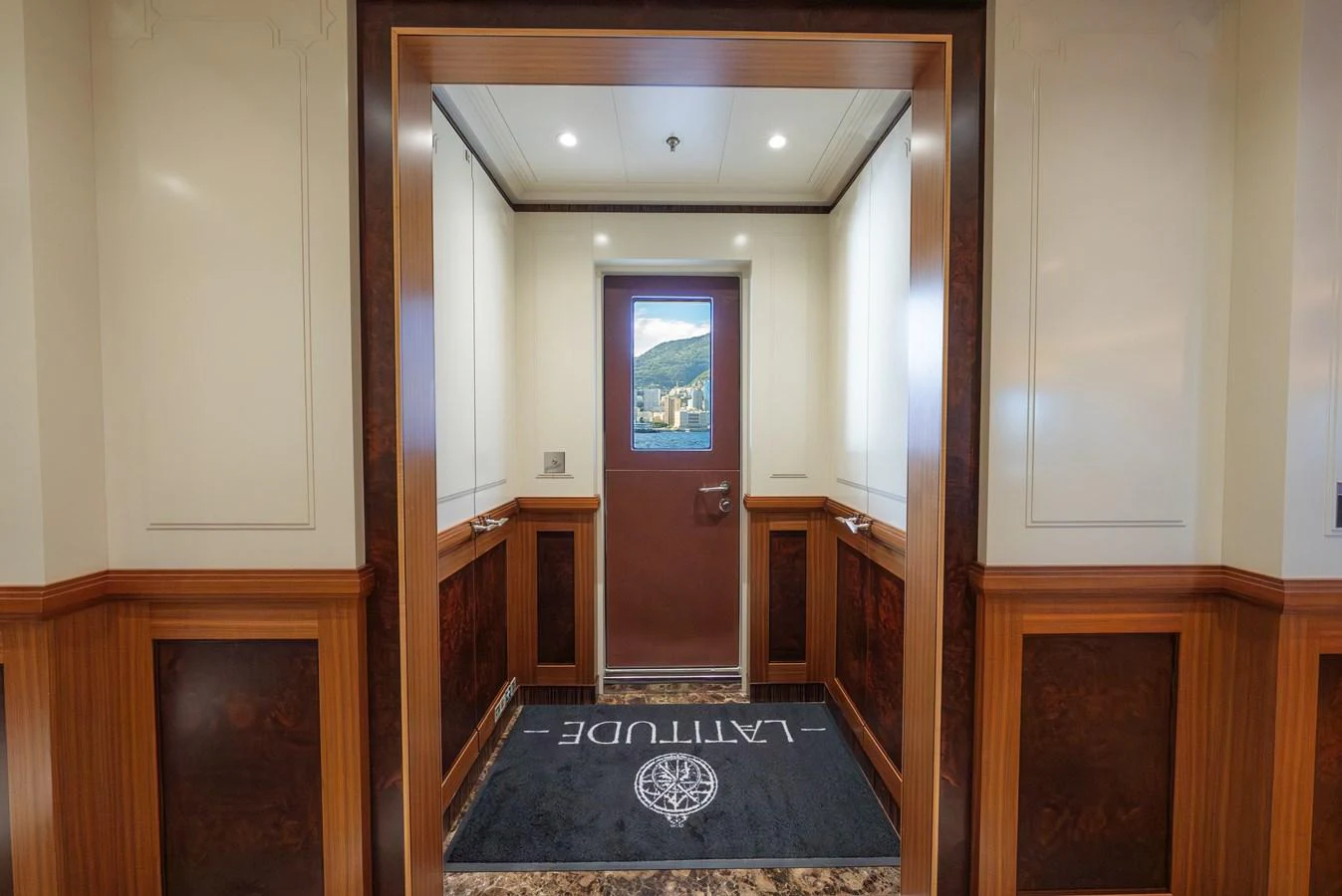 A luxurious interior hallway with elegant wood paneling and a door leading outside. aboard LATITUDE Yacht for Sale