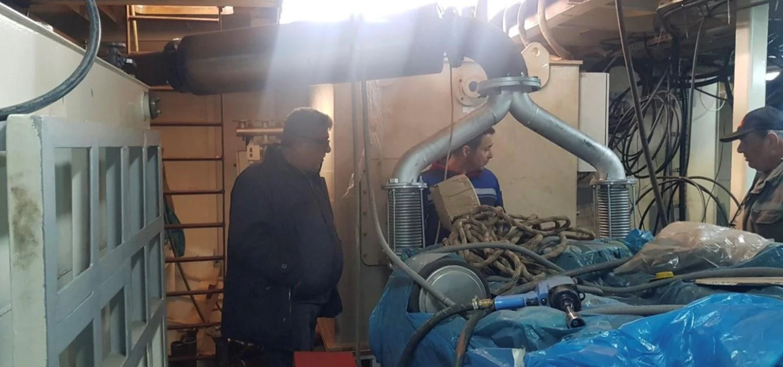 Crew members are working in the yacht's engine room, surrounded by various equipment and tools. aboard NIRVANA Yacht for Sale
