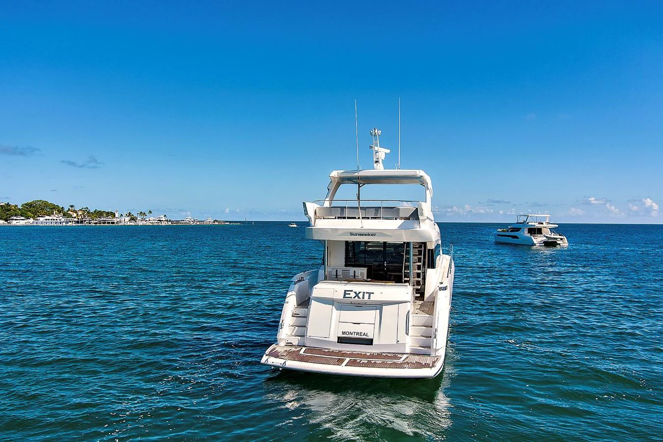 A sleek yacht cruising on calm blue waters under a clear sky. aboard EXIT Yacht for Sale