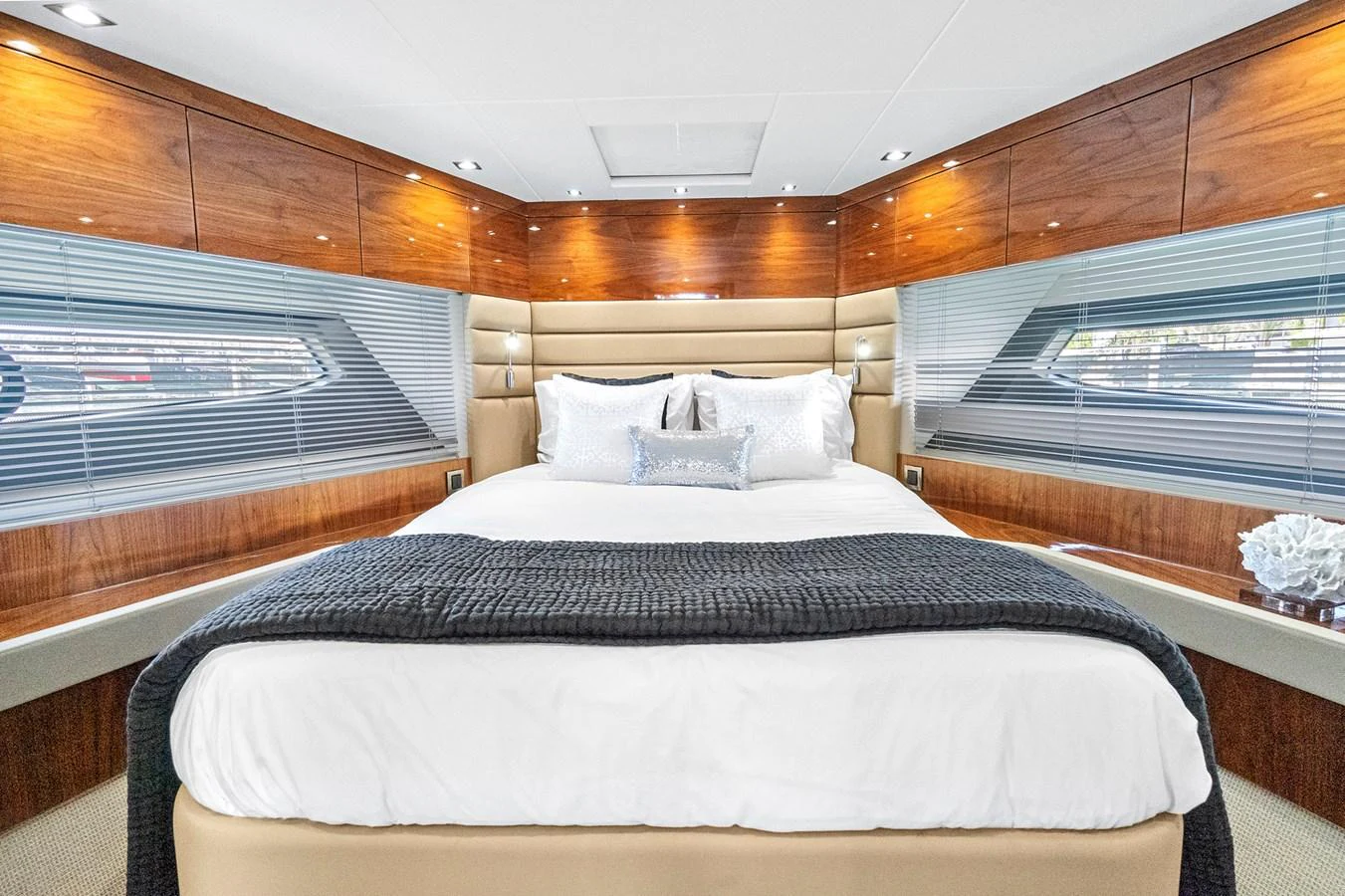 The master stateroom features a luxurious bed with elegant wood paneling and ample natural light. aboard EXIT Yacht for Sale