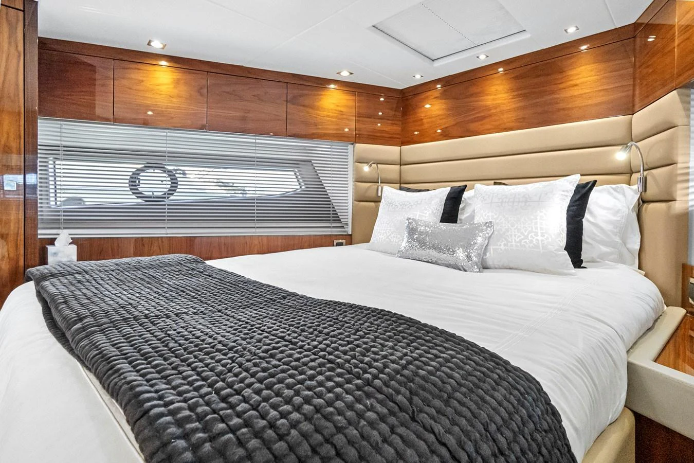 The stateroom features a luxurious bed with elegant wood paneling and modern lighting. aboard EXIT Yacht for Sale