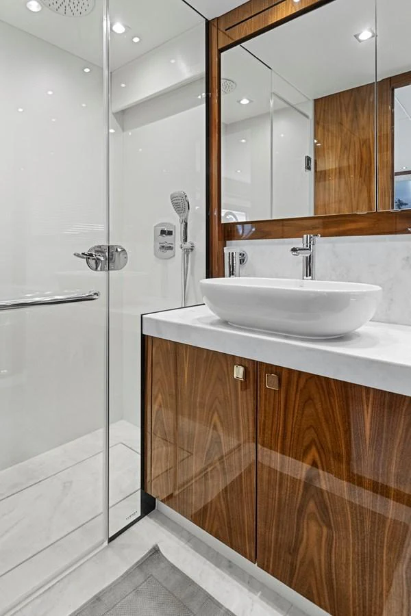 A modern yacht bathroom featuring sleek wood cabinetry and a stylish vessel sink. aboard EXIT Yacht for Sale