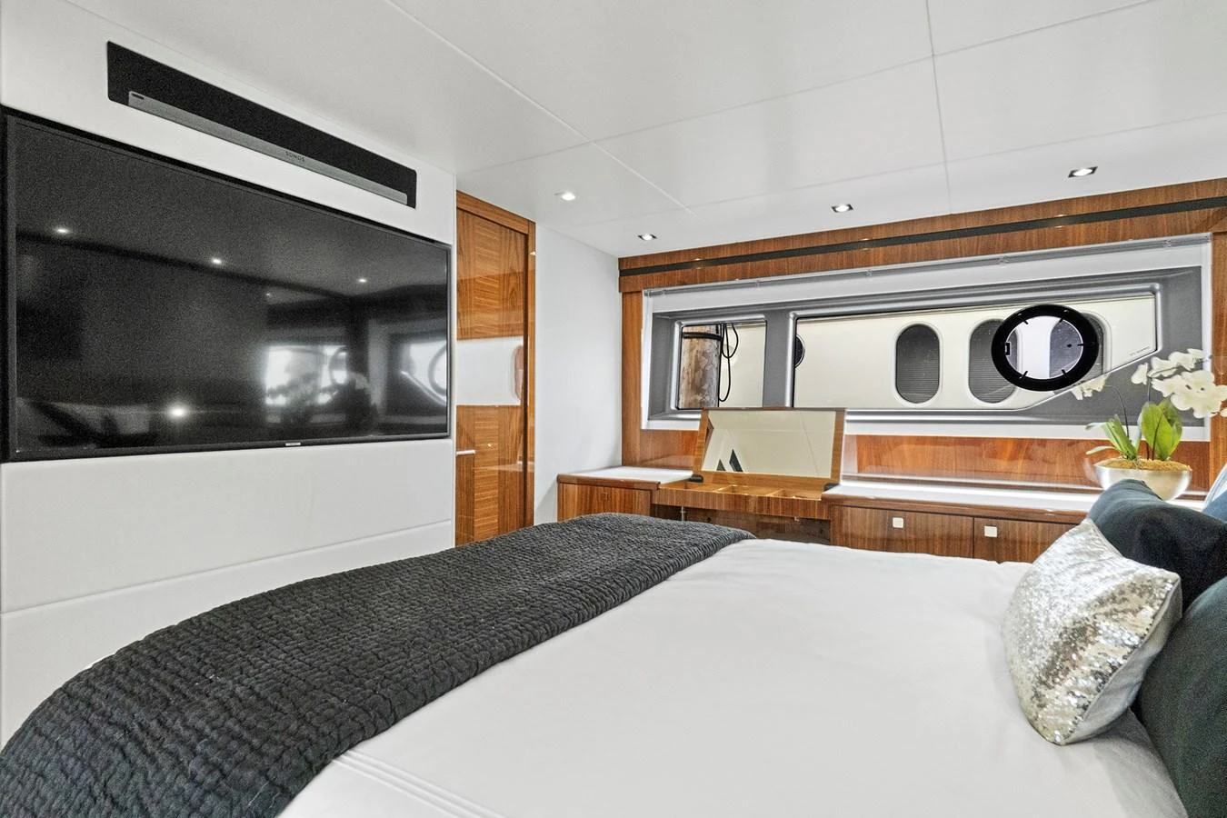 A luxurious stateroom featuring a large flat-screen TV, elegant wood finishes, and a comfortable bed with plush pillows. aboard EXIT Yacht for Sale