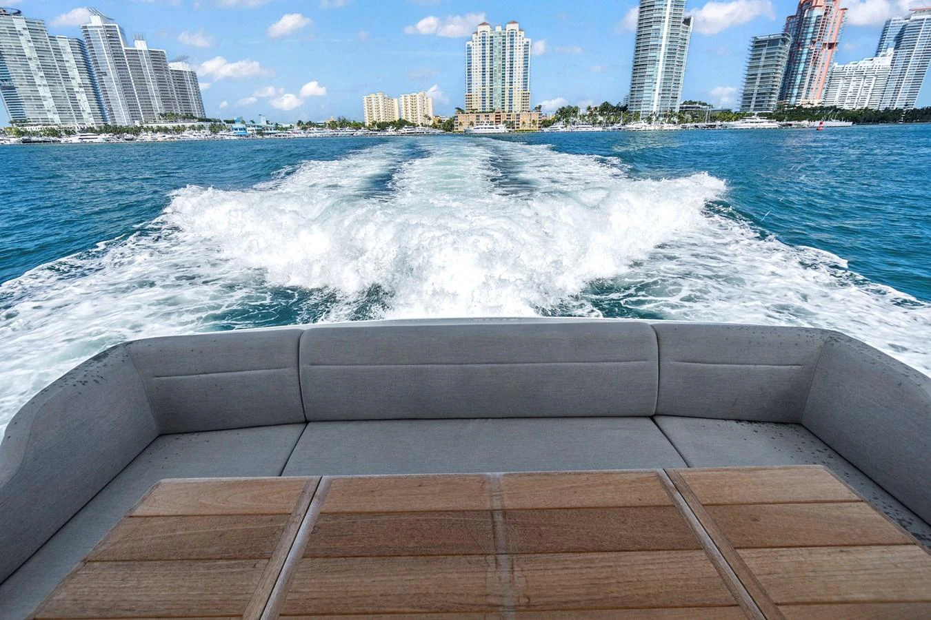 The aft deck offers a relaxing space with a view of the city skyline and the yacht's wake trailing behind. aboard EXIT Yacht for Sale