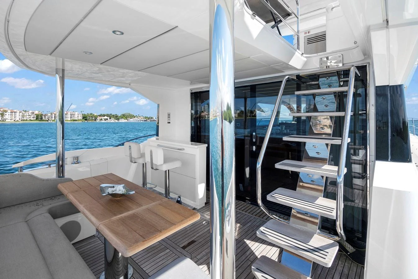 The aft deck features a sleek staircase and a comfortable seating area with a view of the water. aboard EXIT Yacht for Sale