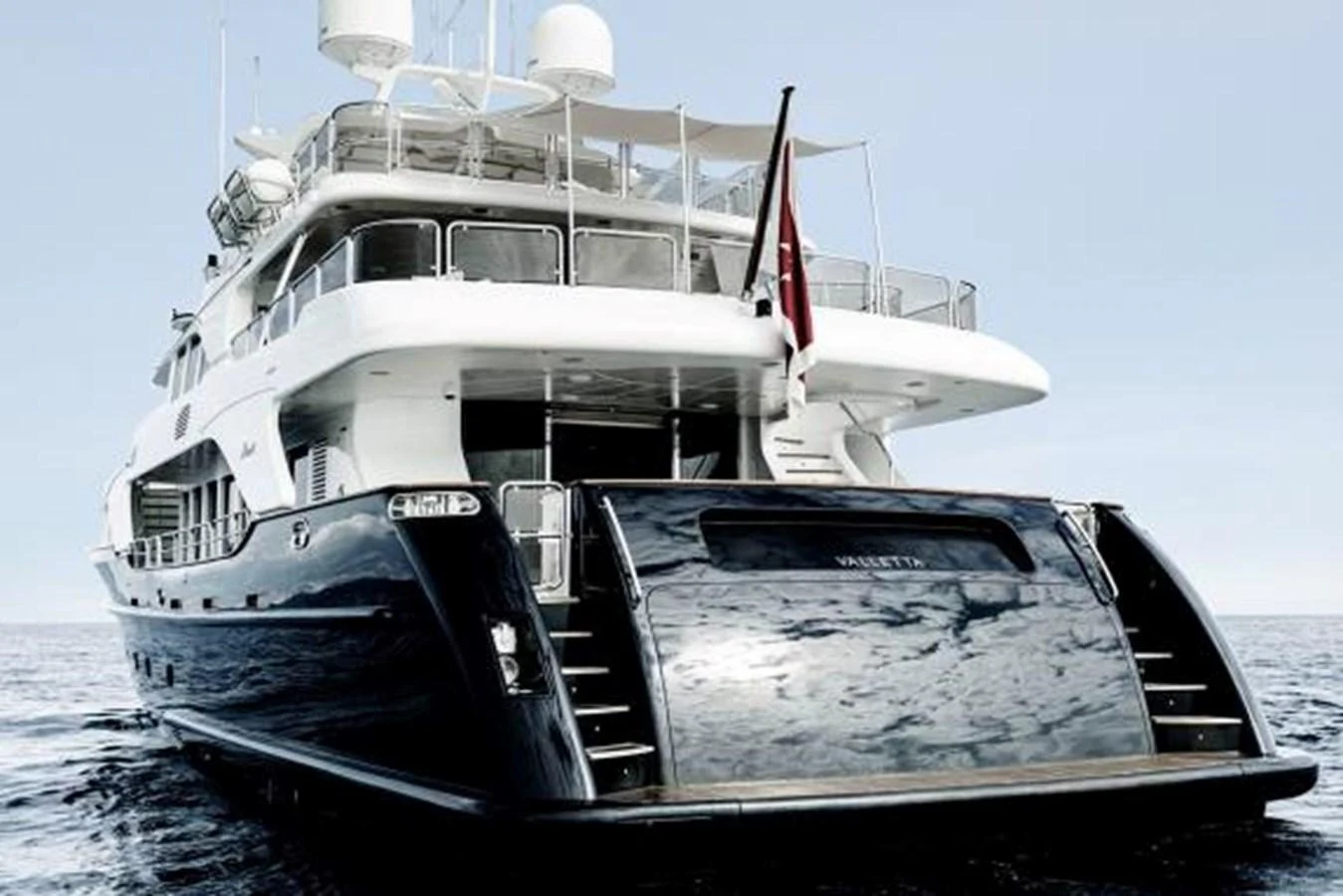 A luxurious yacht with a sleek design is anchored on calm waters. aboard SOHO Yacht for Sale