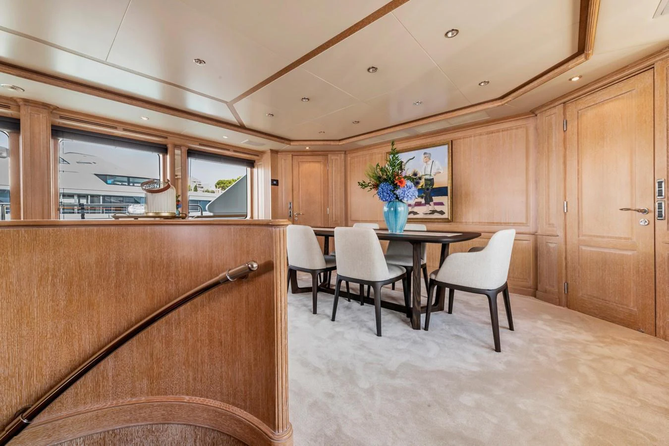 The yacht's dining area features elegant wood paneling, plush carpeting, and a stylish table with comfortable seating. aboard SOHO Yacht for Sale