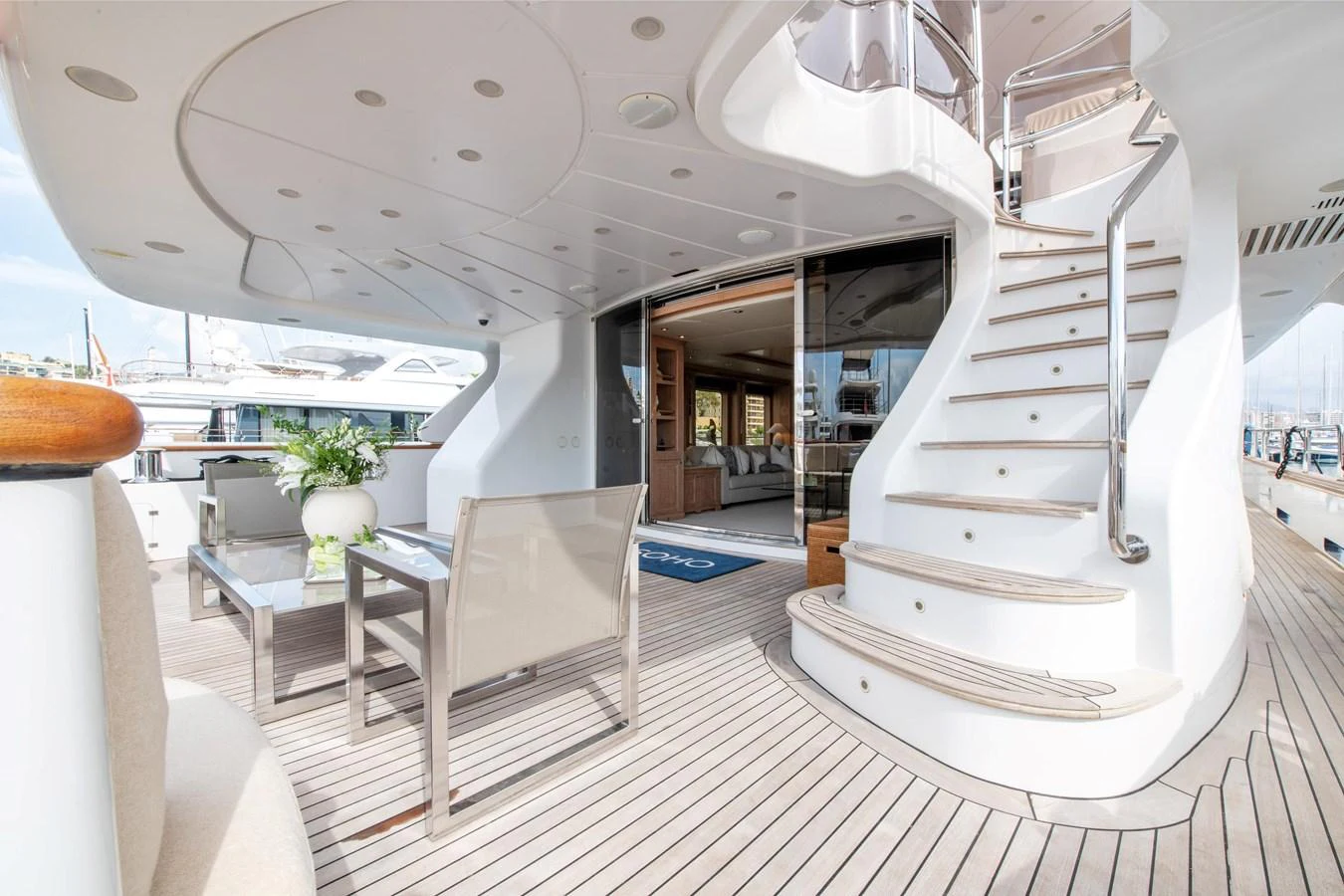 The aft deck features elegant seating and a stylish staircase leading to the upper deck. aboard SOHO Yacht for Sale