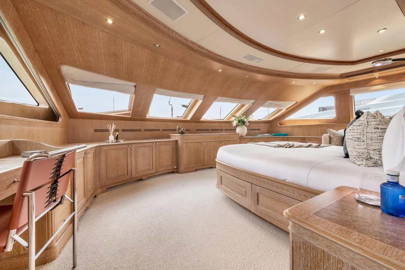 The master stateroom features expansive windows, luxurious bedding, and elegant wood finishes. aboard SOHO Yacht for Sale