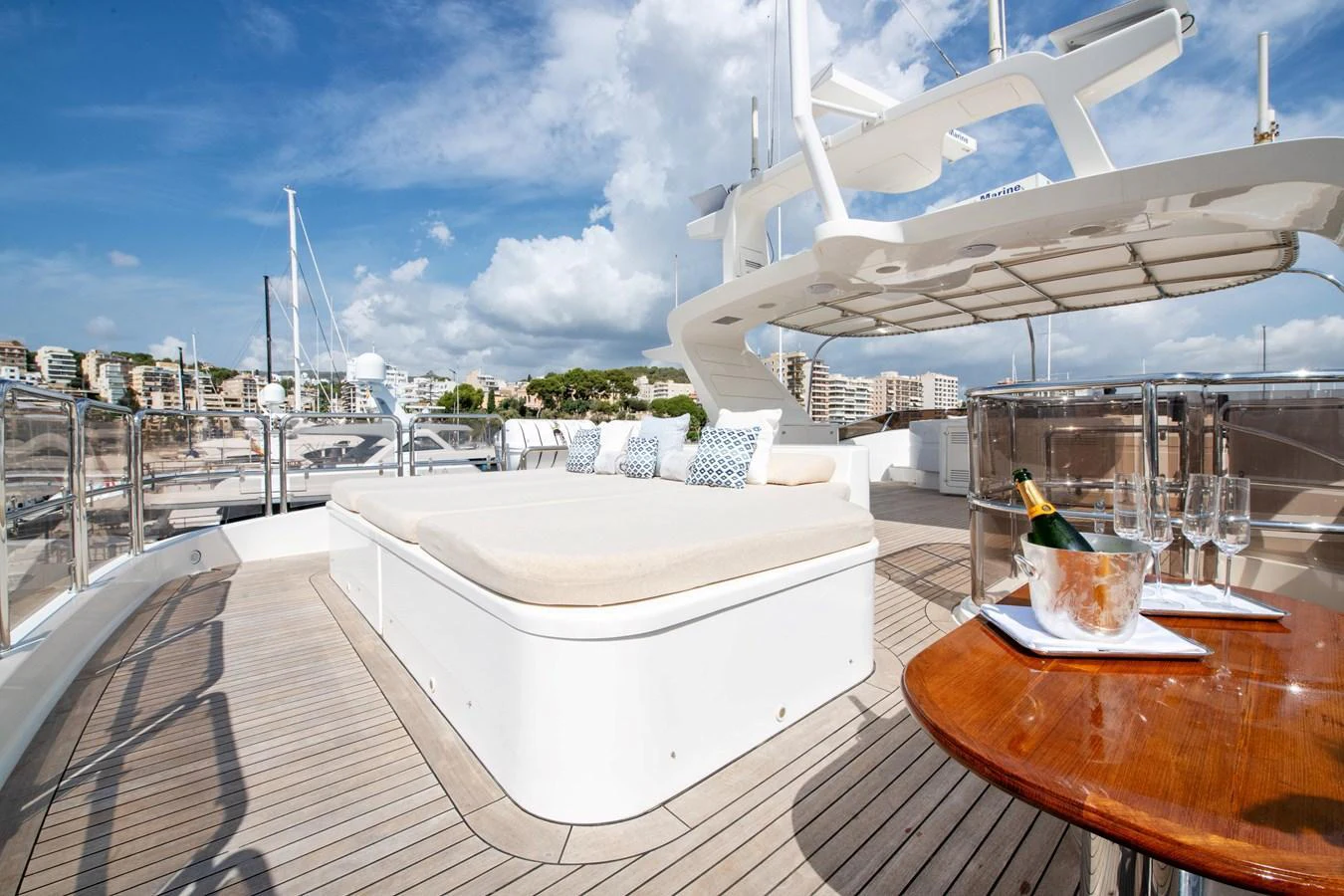 The sundeck offers a luxurious lounging area with plush cushions and a table set for champagne. aboard SOHO Yacht for Sale