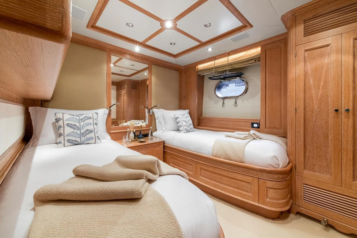 The guest cabin features twin beds with elegant wooden furnishings and soft lighting. aboard SOHO Yacht for Sale