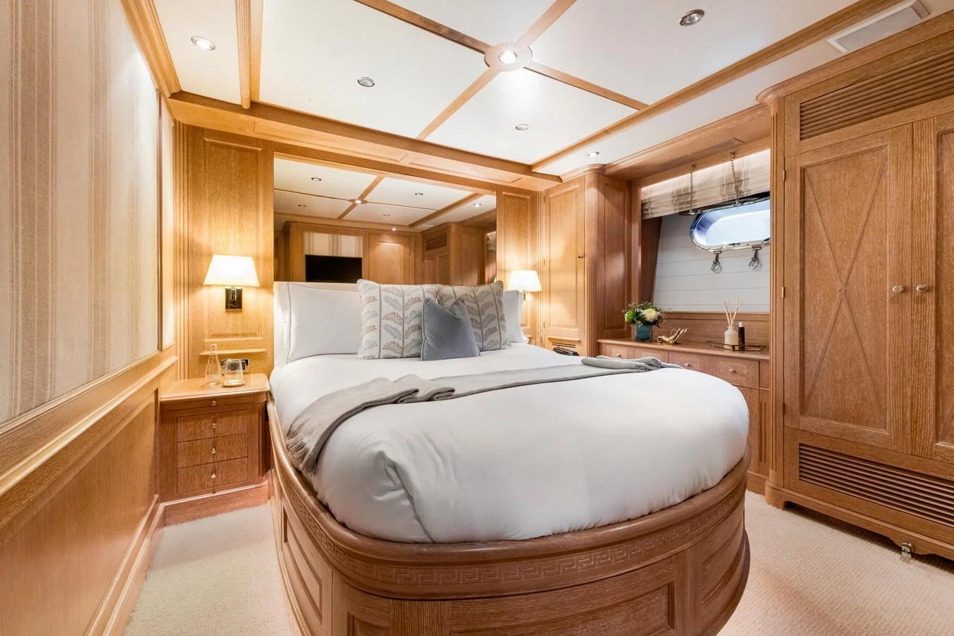 The stateroom features a luxurious bed with elegant wood paneling and ambient lighting. aboard SOHO Yacht for Sale