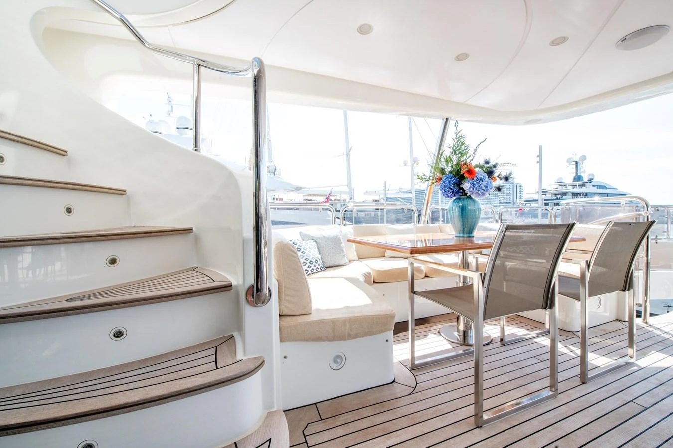 The aft deck features a stylish dining area with a staircase leading to the upper deck. aboard SOHO Yacht for Sale