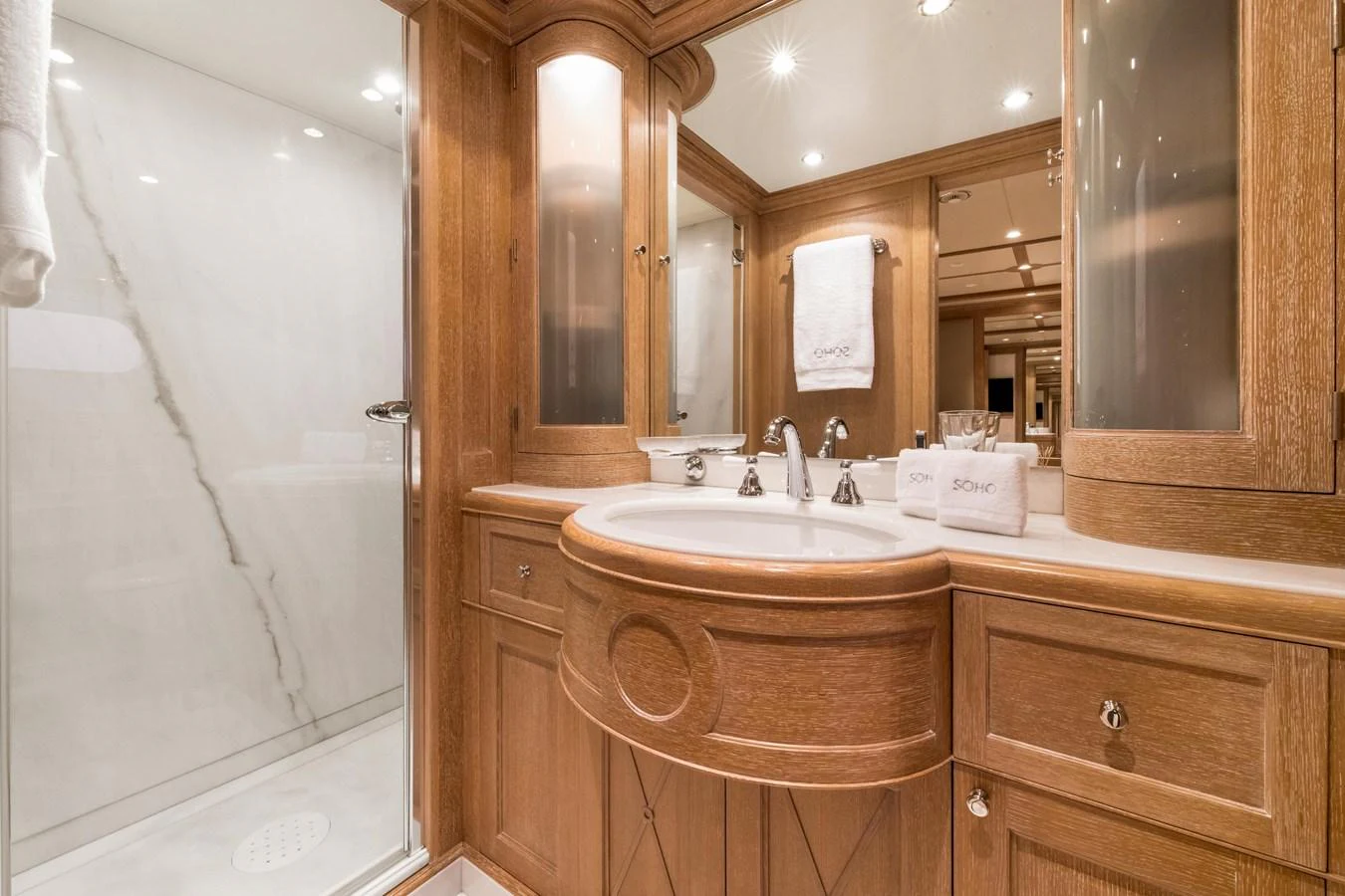 The yacht's bathroom features elegant wood cabinetry and a spacious shower area. aboard SOHO Yacht for Sale