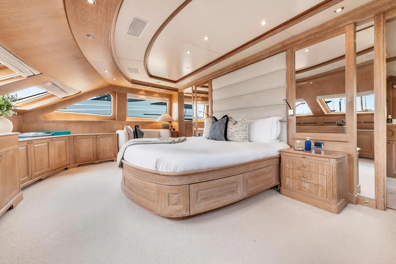 The master stateroom features a luxurious bed with elegant wood finishes and ample natural light. aboard SOHO Yacht for Sale