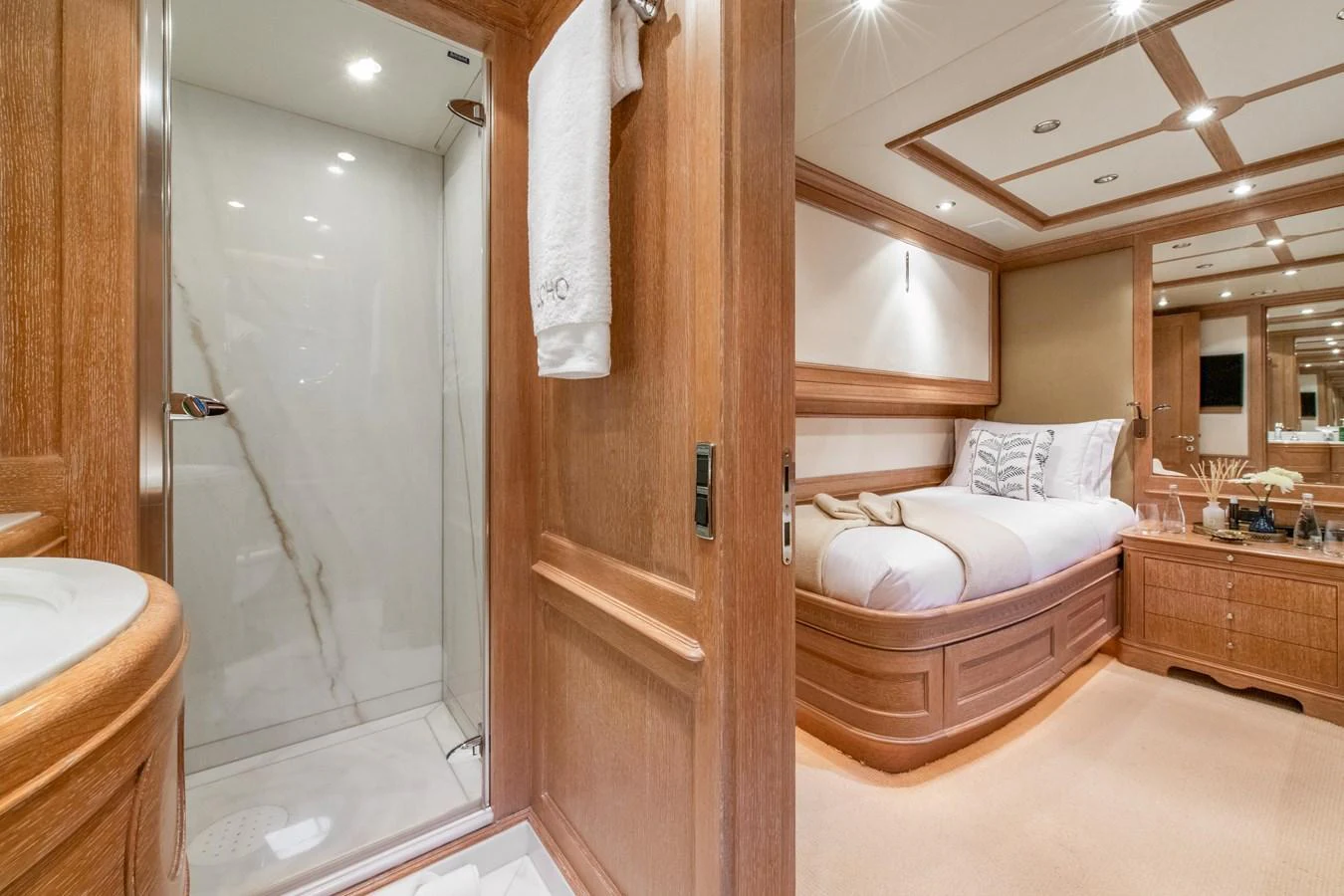 The guest stateroom features elegant wood paneling and a cozy bed, with an adjacent en-suite bathroom. aboard SOHO Yacht for Sale