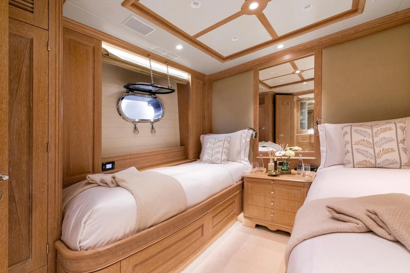 The guest stateroom features twin beds with elegant bedding and warm wood finishes. aboard SOHO Yacht for Sale